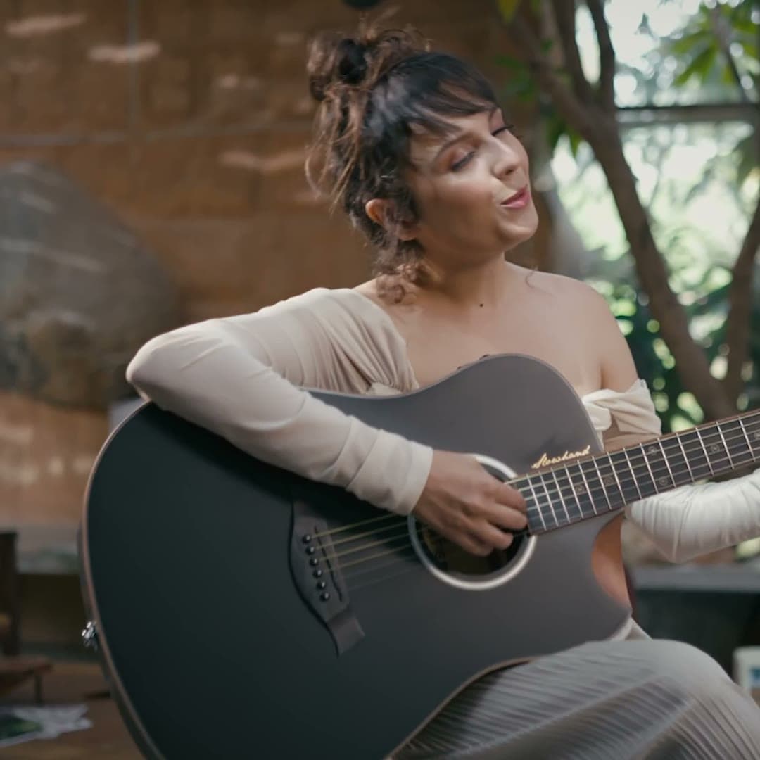 A musician playing a Kadence Slowhand acoustic guitar